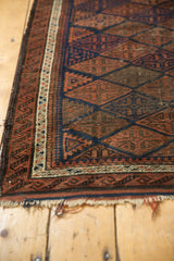 Antique Belouch rug corner: pawn design border, navy and madder red field, storied goat hair selvage.