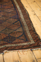 Antique Belouch rug's original plain weave end, showing tattered edge and geometric motifs.