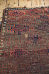 Knot head wear and a patch on antique Belouch rug's geometric gul pattern.