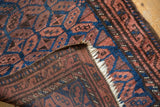 Vintage Belouch rug's corner showcasing chestnut, navy gul motif, hand-knotted reverse, and ivory fringe.