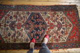 Antique Persian Malayer rug's worn navy diamond medallion, ivory field, and Herati birds.