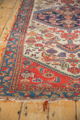 Antique Malayer runner's tattered red and blue border, with Herati motif and tiny birds on an ivory field.