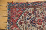 Antique Malayer rug fragment corner, worn red, blue borders, tattered fringe, stylized field patterns.