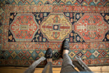 Vibrant geometric medallion and stylized animals on an antique Heriz rug, featuring a green border.