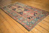 Antique Heriz rug corner featuring unusual celadon green border and madder red geometric and floral motifs.