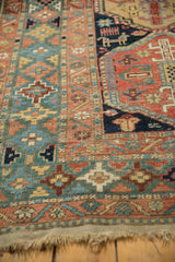 Antique Heriz rug's distinctive green geometric border, madder red field motifs, and natural fringe.