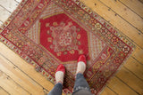 Cherry red Melas rug with floral medallion, budded blossoms, and visible wear.