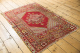 Cherry red, saffron, and blush floral border details on a worn vintage Melas rug corner.