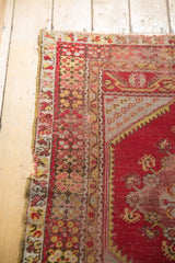 Tattered left edge of vintage Melas rug, showing original selvage and cherry red floral border.