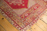Vintage Turkish Melas rug corner showcasing cherry red field and worn saffron floral borders.