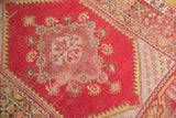 Worn cherry red field and saffron yellow Chintamani clover spandrel on a vintage Melas rug.