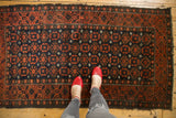 Dense geometric field of charcoal brown and rich brick red, framed by starburst borders.