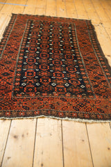 Tattered end of antique Persian Belouch runner, displaying brick red starburst motifs.