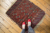 Antique Tekke rug detail: repeating Bokhara gul motifs in chestnut and navy, with worn edges.