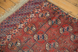 Antique Tekke rug detail: repeating Bokhara gul motifs, chestnut, navy, and brick red, with worn edge.