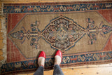Stylized blue and madder red borders on antique Malayer rug corner, fringe visible.