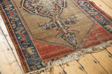 Tattered fringe and worn madder red border with camel ground on this antique Malayer rug.