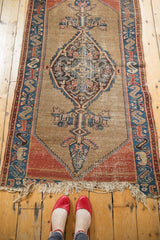 Tattered end fringe of the antique Malayer rug, with madder red, blue, and field wear.