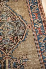 Visible design detail of antique Malayer rug with stepped medallion, camel field, and worn blue border.