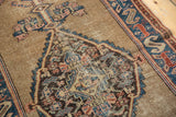 Intricate Persian Malayer rug medallion detail, camel ground with blue, red, pink motifs, and mostly even wear.