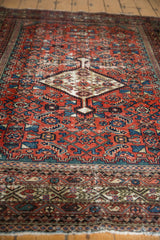 Antique Fereghan rug lower border with madder red field, etched greens, and visible fringe.