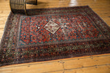 Antique Fereghan rug corner showcasing intricate borders, madder red Herati field, and softened green hues.