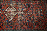 Antique Fereghan rug close-up: madder red field with Herati motif, showing even wear and celadon green etching.