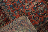 Folded Antique Fereghan rug corner with madder red Herati pile and intricate woven reverse.