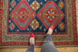 Indigo blue field with serrated red medallion, geometric patterns, and hooked beige border.