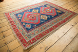 Visible wear on indigo field, bright red medallion, and scrolling stepped border of this antique Caucasian rug.