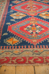 Antique Caucasian rug's red and beige stepped geometric border, indigo field, worn fringe.