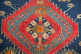 Geometric detail of antique Caucasian rug: serrated red, indigo blue patterns surrounding an orange star.