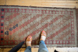 Top left detail of antique Belouch runner, showing etched pile, madder root red and navy geometric patterns.