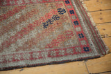 Angled close-up: antique Belouch runner, etched pile, madder red, ivory, navy geometric lattice.