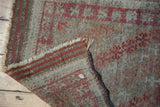 Antique Belouch rug corner revealing etched pile, striped woven end, and fringe.