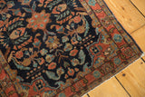 Mohajeran Sarouk rug corner detail: navy floral field, brick red border, visible white knots, tattered end.