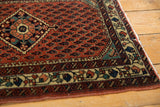 Corner of a vintage Persian rug with a rust-red boteh field and a charismatic, colorful border.