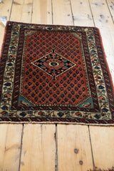 Vintage Engelas rug from an angle, showing the navy diamond medallion and brick red boteh design.