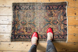 Corner view of antique Persian Lilihan rug displaying faded floral motifs and visible fringe tatter.