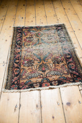 Antique Persian Lilihan rug mat detail, showing dark floral border, worn field with expressive leaf fills, and tattered edge.