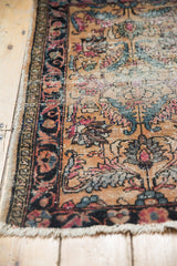Antique Lilihan rug mat close-up: navy, raspberry floral border, and wear to foundation.