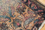 Close-up of the antique Persian Lilihan rug revealing worn knot heads and tattered edge.