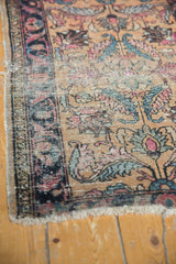 Bottom right corner of antique Lilihan rug displaying floral pattern, worn edge, and tattered fringe.