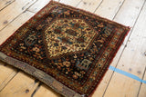 Stylized animal and floral motifs on antique Afshar rug corner in dark navy, wine red.
