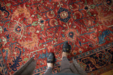 Persian Heriz carpet showcasing geometric and scrolling serrated leaf design in cherry red and navy blue.