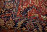 Antique Heriz carpet detail: cherry red field, navy scrolling serrated leaf, circa 1910.