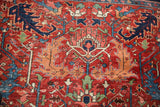 Heriz carpet detail showcasing oversize scrolling serrated leaf design in cherry red, navy, and mallard green.