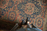 Antique Caucasian Soumac carpet section, displaying dusty brick red and navy blue motifs with exposed foundation.