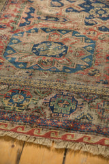 Antique Caucasian Soumac carpet close-up: red wave border, intricate geometric patterns, and exposed foundation.