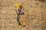 A pair of 6-inch natural beeswax taper candles in a corrugated sleeve tied with a black ribbon.